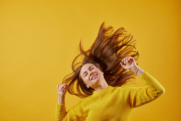 girl in a yellow sweater dancing on a yellow background