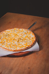 Chopped view of a corn pizza on top of a wooden table.