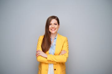 Smiling woman in yellow jacket standing with crossed arms on gray background - 585961321