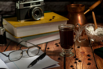 table with books old photo cameras pen notebook and cup of coffee with coffee pot and sugar bowl
