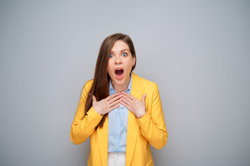 Excited surprising woman in yellow jacket on gray background
