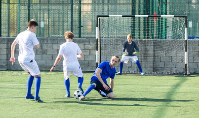 Fototapeta premium Youthful football players challenging for ball in midfield zone