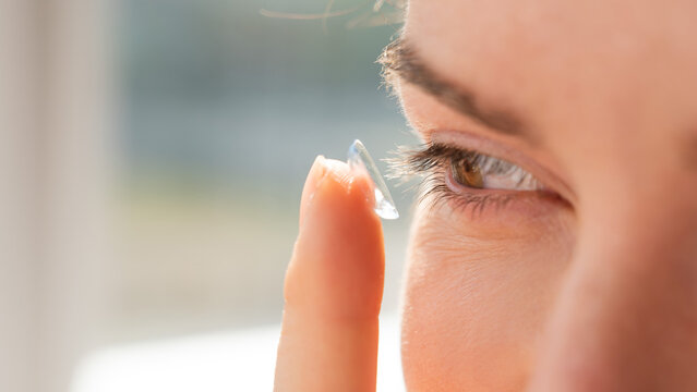 Close-up portrait caucasian woman putting on a contact lens. 