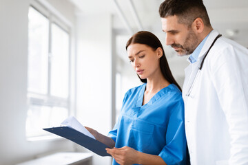 Team of doctors working together on patients file, analyzing report, having discussion in hospital office, copy space