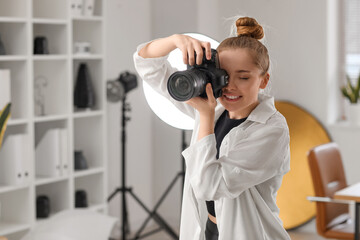 Young female photographer with professional camera working in studio - obrazy, fototapety, plakaty