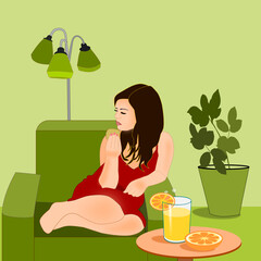 A young girl is sitting and relaxing in an armchair with a glass of juice and two half oranges on a table in front of her.
