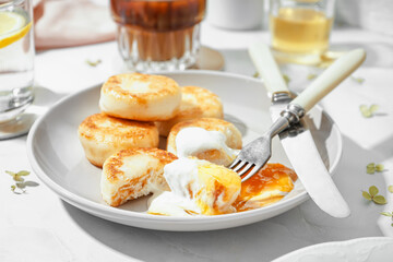 Plate of tasty cottage cheese pancakes with sour cream and jam on light table