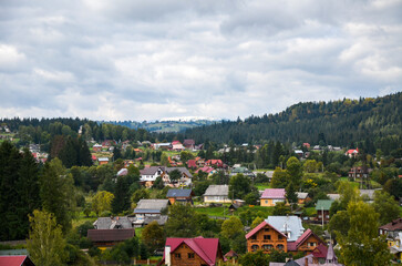 Fototapeta premium Panorama of the green hilly valley with houses and a mountainous backdrop at the Vorokhta village, Carpathian Mountains, Ukraine