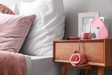 Sex toys with clock and frame on table in bedroom, closeup