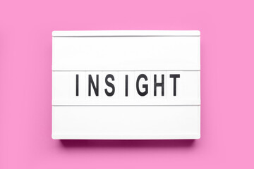 Board with word INSIGHT on pink background