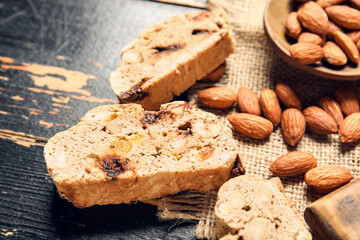 Delicious biscotti cookies and almond nuts on black wooden background, closeup
