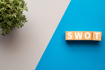 There is wood cubes with the word SWOT. It is an abbreviation for strengths, weaknesses,...