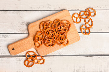 Board with tasty pretzels on light wooden background