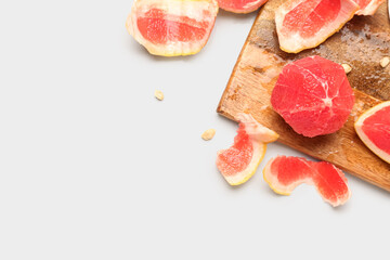 Wooden board with peeled grapefruit on white background