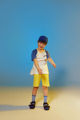 Cheerful emotional boy in a cap at blue and yellow color studio background