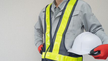 ヘルメットを持つ作業服の男性｜建設業・警備員・ガードマン　イメージ