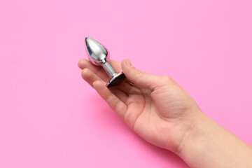Woman with anal plug on pink background, closeup