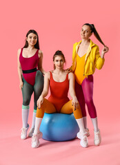 Portrait of sporty young women with fitball on pink background