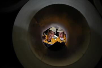 two engineers seen through a large pipeline shaft, metal industry