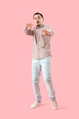 Scared young man on pink background