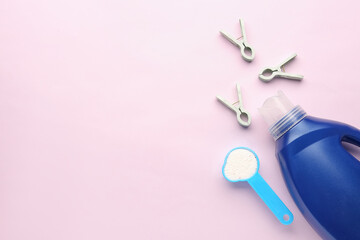 Laundry detergents and clothespins on pink background