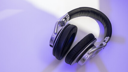 Silver headphones on neon background. Bass headphones