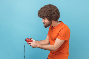 Man holding in hands red gamepad joystick, grimacing playing video games. © khosrork