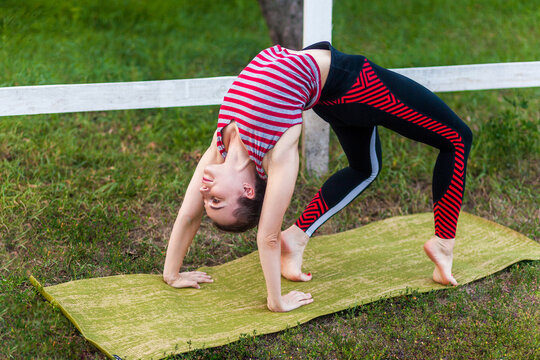 Yogi woman practicing yoga, stretching in wheel exercise, urdhva dhanurasana pose working out on mat