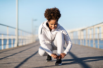 Sporty Black Woman Getting Ready For Jogging Outdoors, Tying Her Shoe Laces