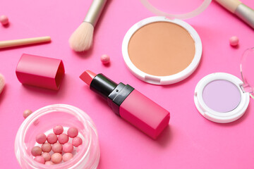 Decorative cosmetics with makeup brushes on pink background, closeup