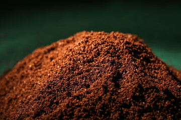 Heap of coffee powder on green background, closeup
