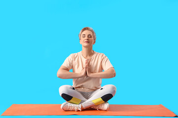 Mature woman meditating on light blue background