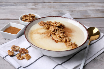 Bowl of tasty semolina porridge with nuts on wooden table