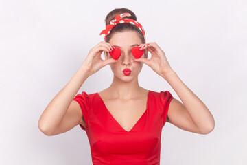 Romantic woman covering her eyes with little red hearts, symbol of love, sending air kissing.