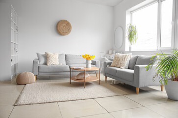 Interior of modern living room with cozy sofas and flower vase on coffee table