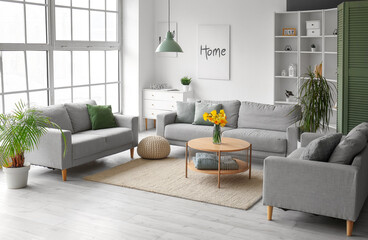 Interior of modern living room with grey sofas and flower vase on coffee table