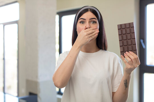 pretty young woman covering mouth with a hand and shocked or surprised expression. chocolate concept