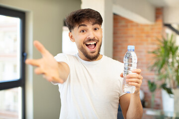 young handsome man smiling happily and offering or showing a concept. water bottle concept