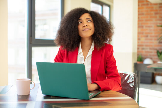 pretty afro black woman smiling with a happy, confident expression with hand on chin. businesswoman and laptop concept