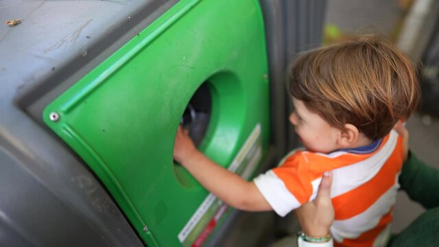 Little boy recycling glass into city recycle dispenser