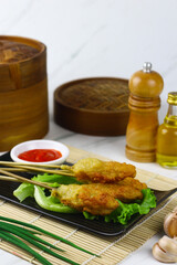Sempol ayam or fried chicken satay, one ofpopular street food in Indonesia.  Served with chili sauce. White marble background.