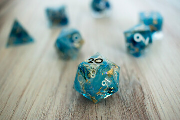 Blue resin dice with glitter inclusions on wooden surface