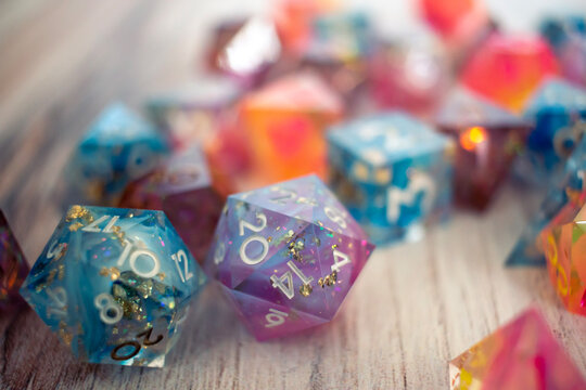 Resin dice on a wooden table, a blue die and purple die sit in the foreground