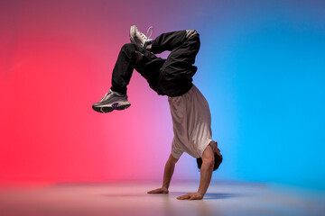 dancer doing acrobatic trick and dancing breakdance in neon red and blue lighting