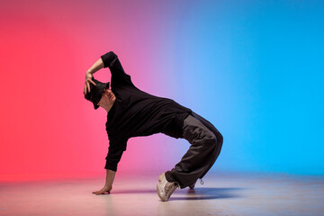 dancer doing acrobatic trick and dancing breakdance in neon red and blue lighting