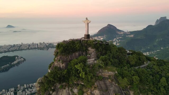 Rio de Janeiro, Brazil - March 21, 2023: Christ the Redeemer statue on top of the Corcovado Mountain with the Sugarloaf Mountain in the  horizon on sunrise.