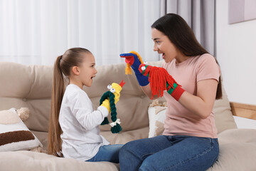 Emotional mother and daughter playing with funny sock puppets together at home