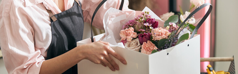 Professional florist young woman is doing bouquets at flower shop - obrazy, fototapety, plakaty