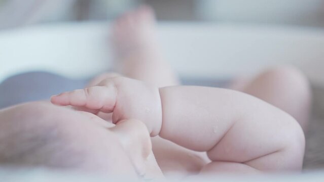Baby eating his finger in bathtub, cute Caucasian white newborn fingers playful mood
