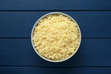 Bowl of tasty couscous on blue wooden table, top view